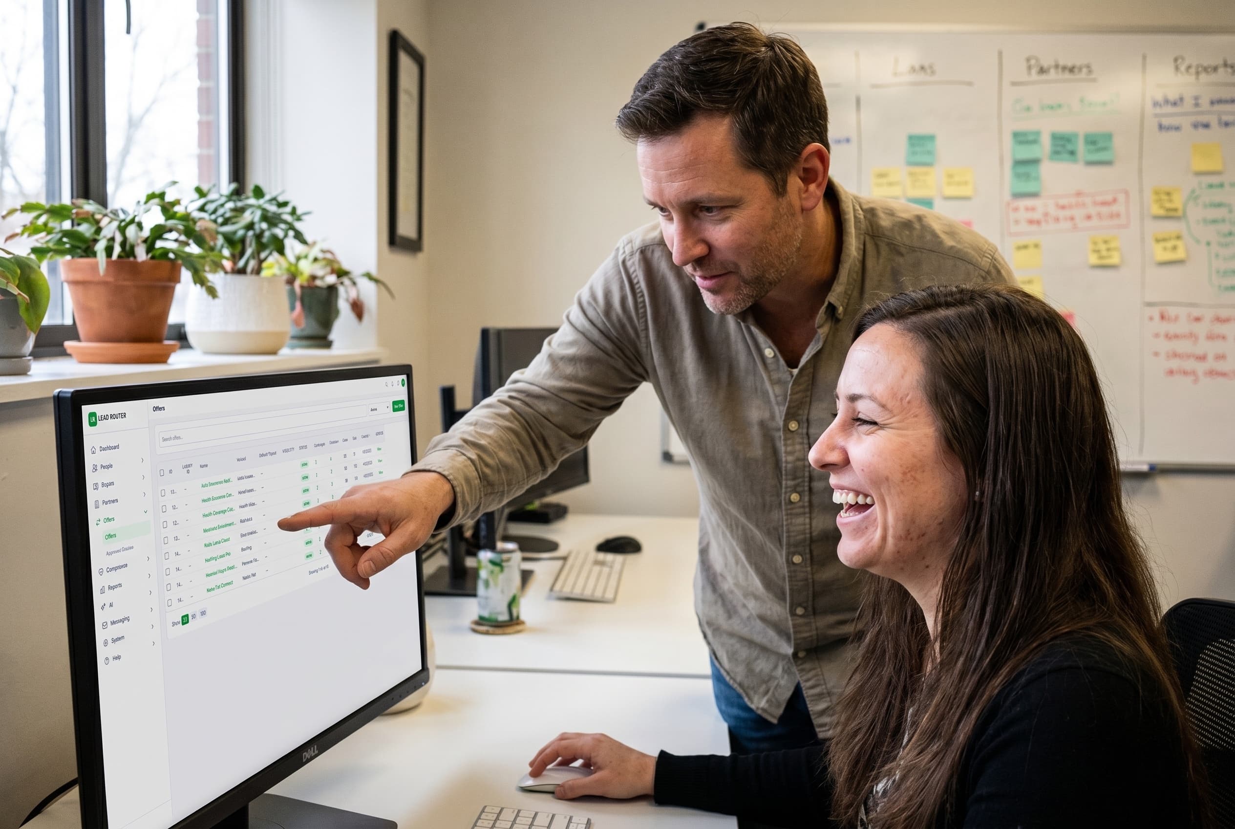 Two colleagues reviewing a list of offers on a monitor